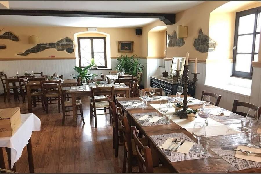 La sala: tavoli in legno, sedie rustiche e dettagli in pietra nelle pareti